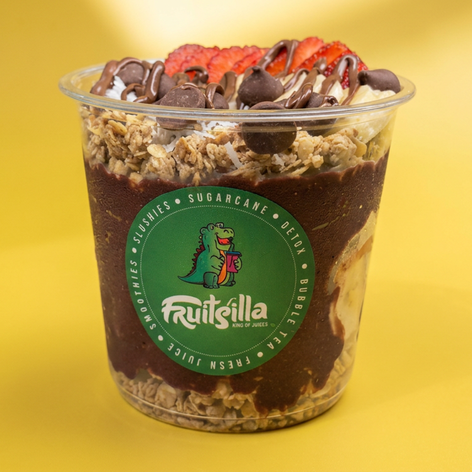 Fruitsilla chocolate parfait layered with granola, topped with chocolate chips, drizzle, whipped cream, and strawberries in a clear cup.